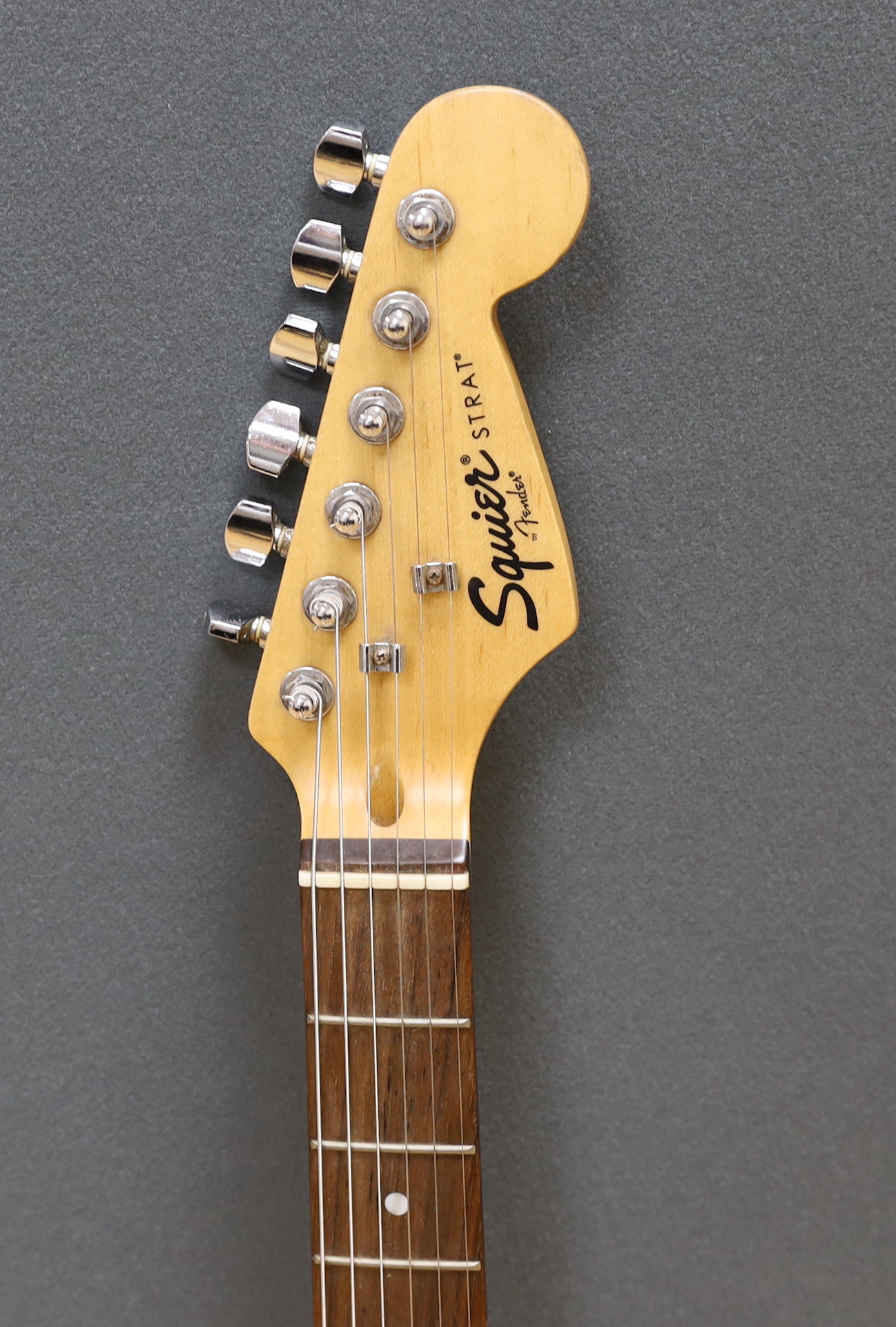 A Squier Strat by Fender electric guitar with rosewood neck and red lacquer body